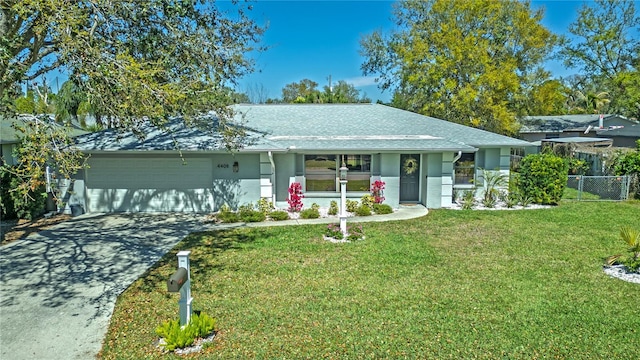 ranch-style house featuring a front yard, fence, driveway, an attached garage, and stucco siding