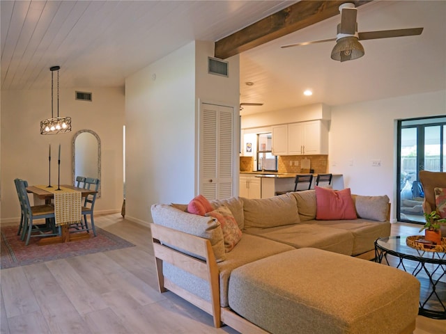 living room with vaulted ceiling with beams, baseboards, visible vents, and light wood finished floors