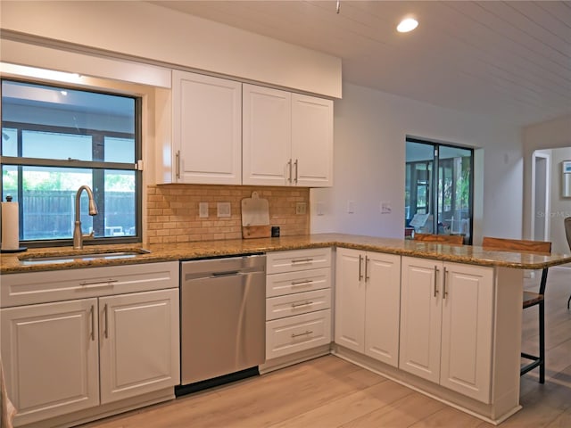 kitchen featuring dishwasher, a peninsula, light wood-style floors, white cabinetry, and a sink