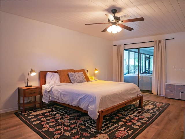 bedroom featuring baseboards, wood finished floors, a ceiling fan, and access to outside