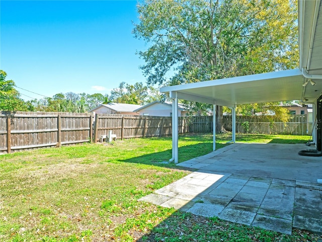 view of yard with a patio area, a fenced backyard, and a carport