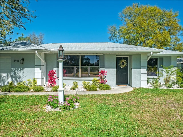 view of front of property featuring a front lawn, an attached garage, and stucco siding