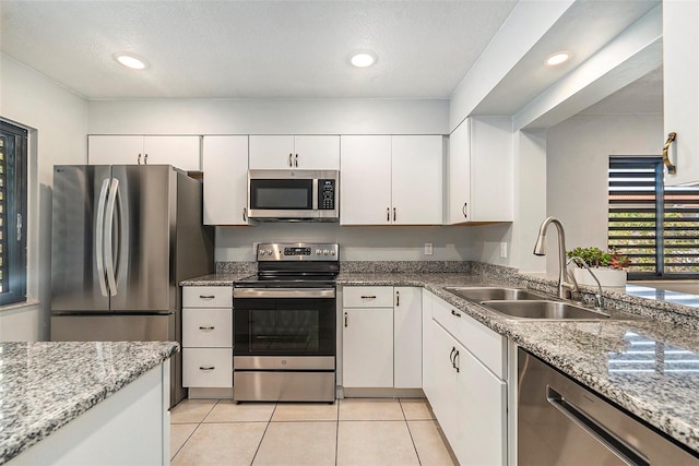 kitchen featuring light tile patterned floors, recessed lighting, a sink, stainless steel appliances, and white cabinetry