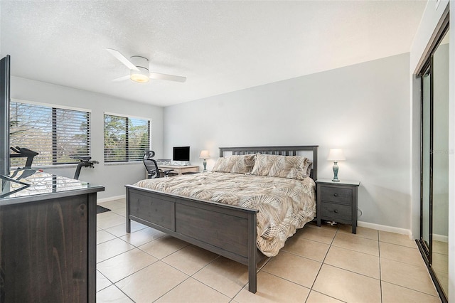 bedroom with light tile patterned flooring, ceiling fan, a textured ceiling, and baseboards