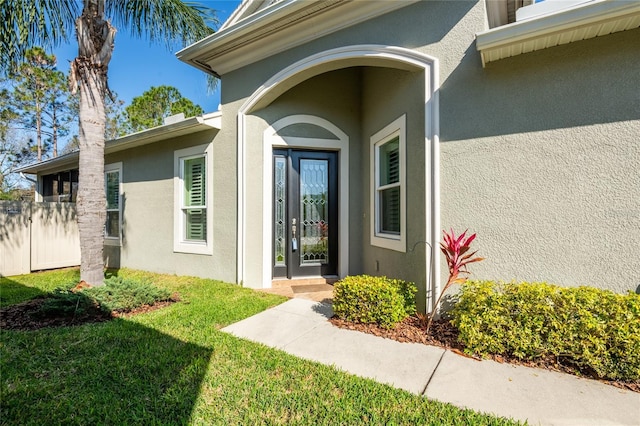 doorway to property with a yard and stucco siding