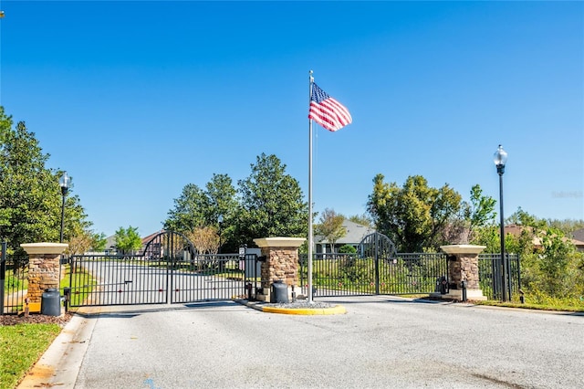 view of street with a gated entry, curbs, street lighting, and a gate