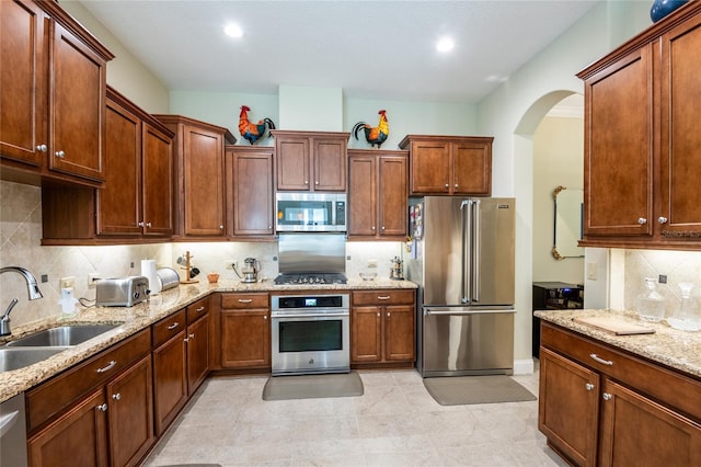 kitchen featuring a sink, light stone counters, recessed lighting, stainless steel appliances, and decorative backsplash