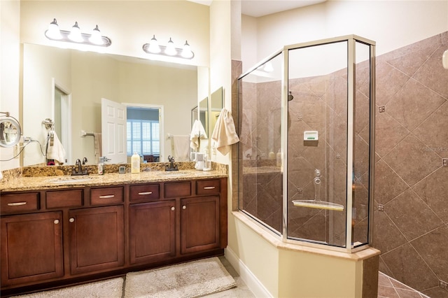 full bath featuring double vanity, a tile shower, and a sink