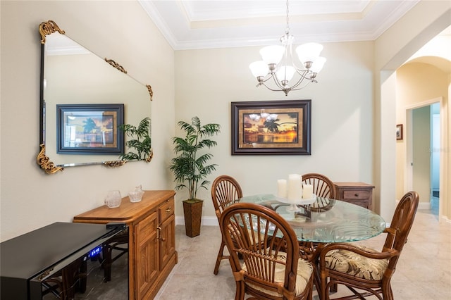 dining space featuring ornamental molding, a tray ceiling, arched walkways, baseboards, and a chandelier