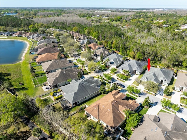 aerial view with a wooded view, a residential view, and a water view