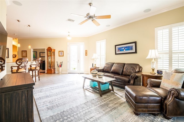 tiled living room with baseboards, a ceiling fan, visible vents, and ornamental molding