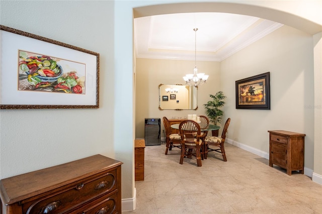 dining area featuring baseboards, arched walkways, ornamental molding, a raised ceiling, and a chandelier