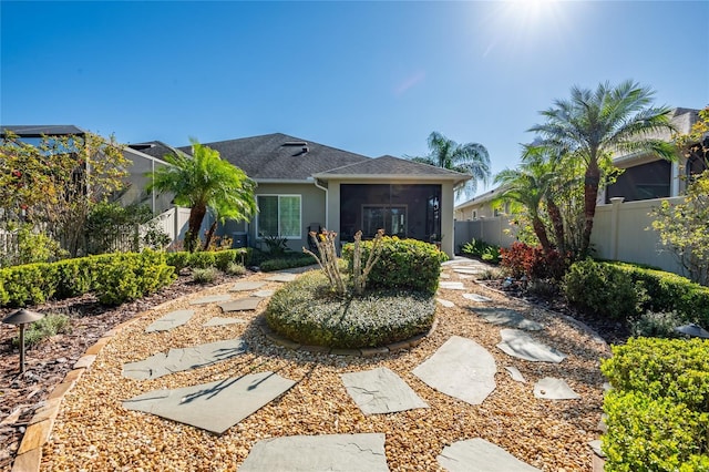 back of property with a fenced backyard, a sunroom, and stucco siding