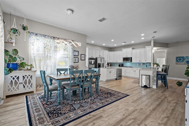 dining area with light wood-style flooring, recessed lighting, beverage cooler, and visible vents