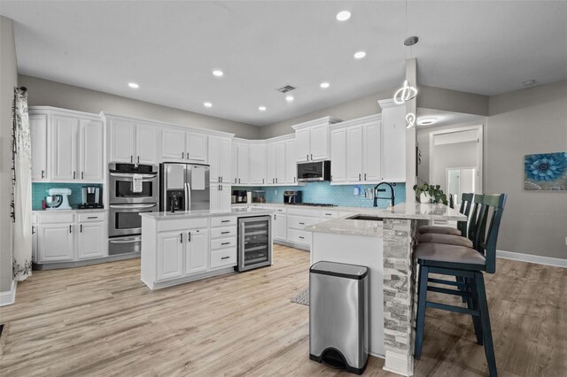 kitchen featuring a sink, white cabinetry, wine cooler, appliances with stainless steel finishes, and a peninsula