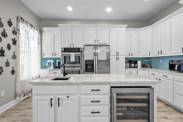 kitchen with a sink, wine cooler, light wood-type flooring, and stainless steel appliances