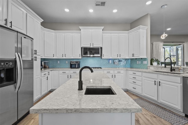 kitchen featuring white cabinets, visible vents, appliances with stainless steel finishes, and a sink