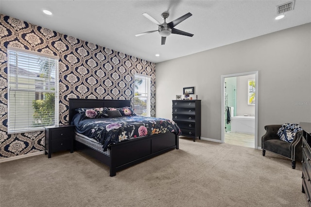 carpeted bedroom featuring wallpapered walls, baseboards, visible vents, and connected bathroom