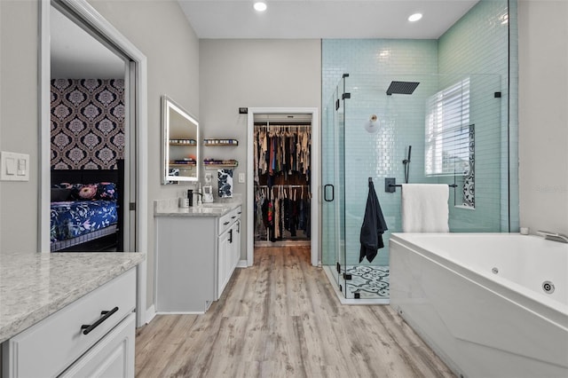 bathroom with a jetted tub, a shower stall, wood finished floors, and vanity