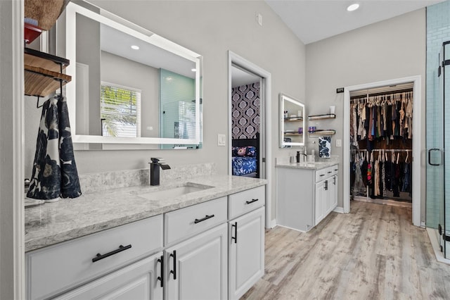 full bath with a spacious closet, a shower stall, recessed lighting, wood finished floors, and vanity