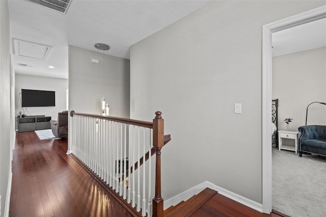 hallway with an upstairs landing, visible vents, baseboards, and wood-type flooring