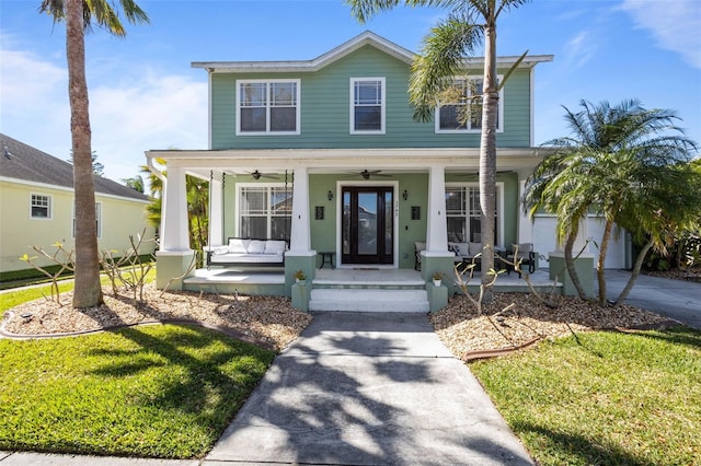 view of front facade with a front lawn, a ceiling fan, a porch, concrete driveway, and an attached garage