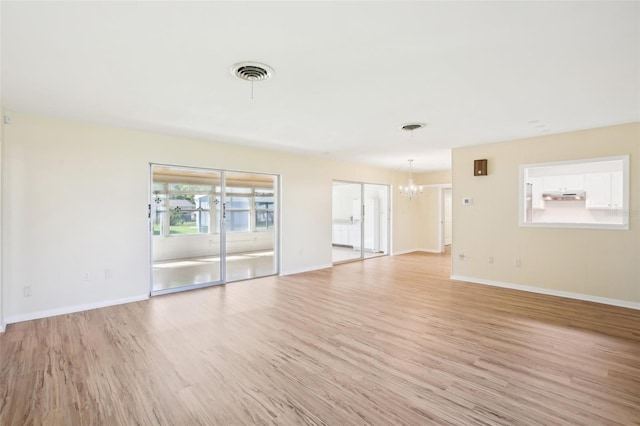 unfurnished living room with a notable chandelier, light wood-style flooring, baseboards, and visible vents