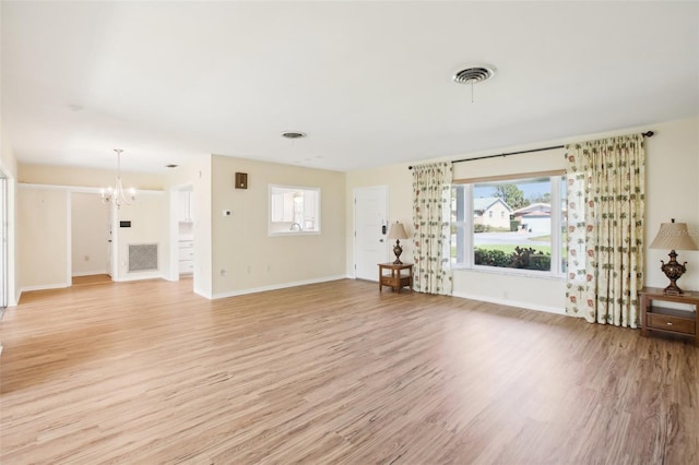 unfurnished living room with light wood-style floors, a notable chandelier, and visible vents