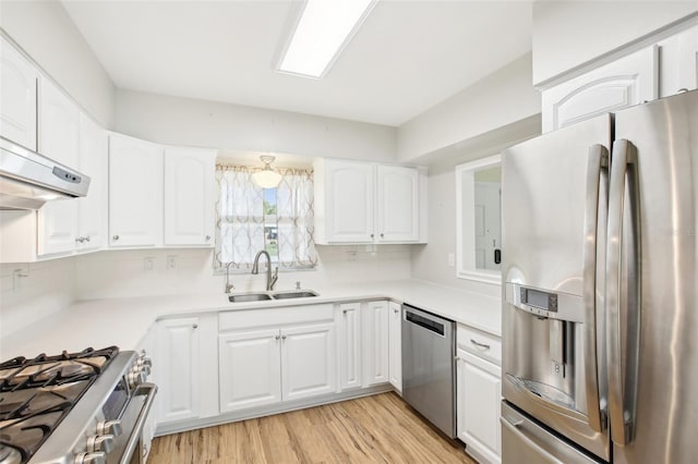 kitchen with light wood finished floors, light countertops, appliances with stainless steel finishes, white cabinets, and a sink