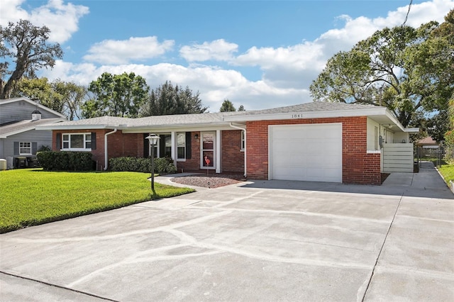 ranch-style house featuring a garage, driveway, brick siding, and a front lawn