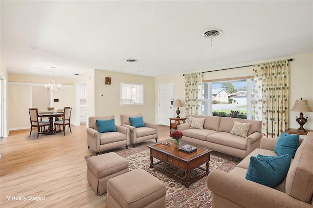 living area featuring a chandelier, visible vents, baseboards, and light wood-style floors