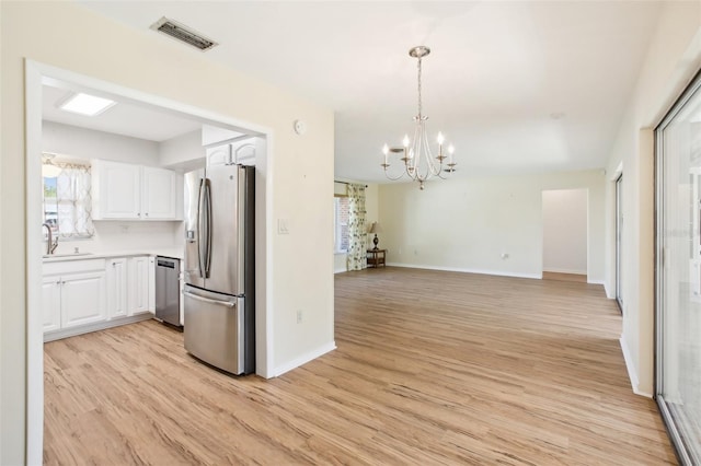 kitchen featuring visible vents, an inviting chandelier, white cabinets, stainless steel appliances, and a sink