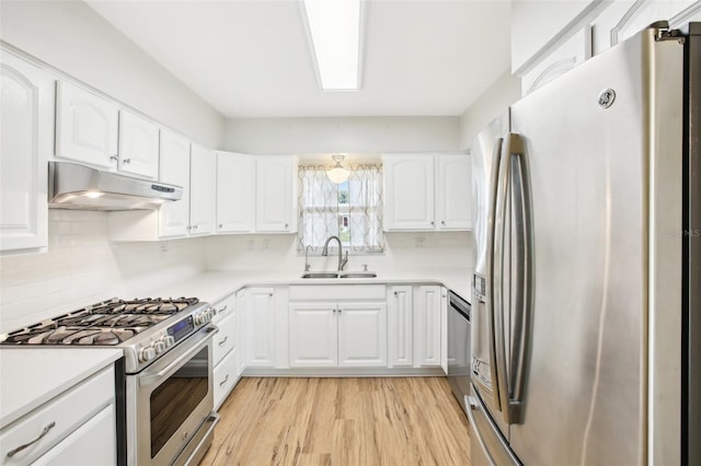 kitchen with under cabinet range hood, light wood-style flooring, appliances with stainless steel finishes, white cabinets, and a sink