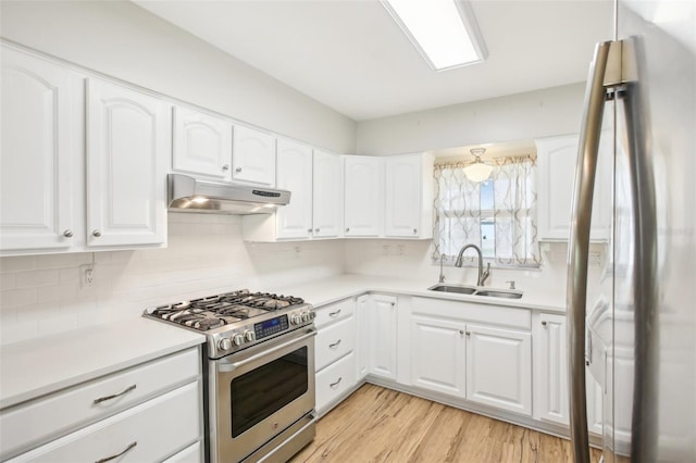 kitchen featuring light wood-type flooring, under cabinet range hood, a sink, appliances with stainless steel finishes, and decorative backsplash