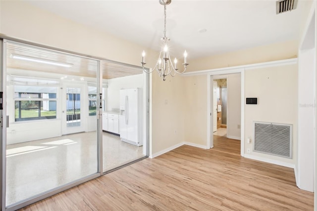 spare room featuring visible vents, light wood-type flooring, and an inviting chandelier