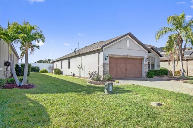 view of side of home featuring driveway, an attached garage, a yard, stucco siding, and stone siding