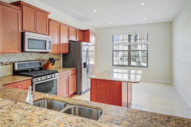 kitchen featuring backsplash, a center island, appliances with stainless steel finishes, baseboards, and light stone countertops