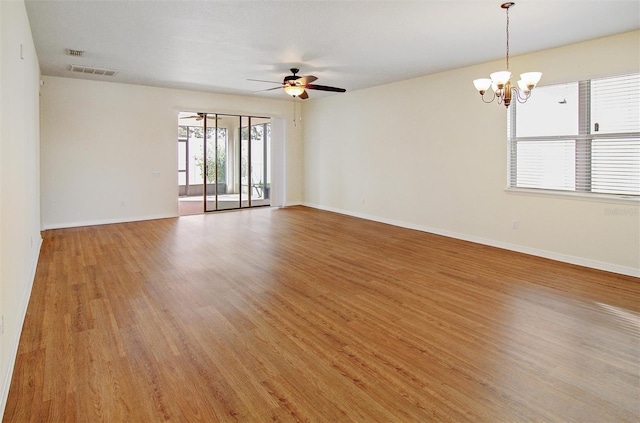 spare room with visible vents, ceiling fan with notable chandelier, baseboards, and light wood finished floors