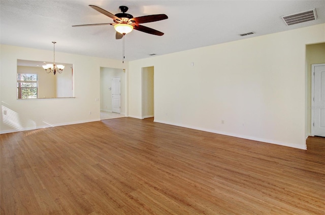 unfurnished living room with ceiling fan with notable chandelier, baseboards, visible vents, and light wood finished floors