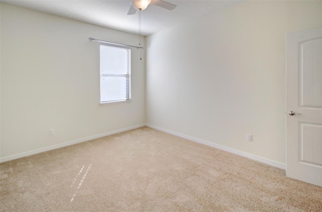 unfurnished room featuring light colored carpet, a ceiling fan, and baseboards