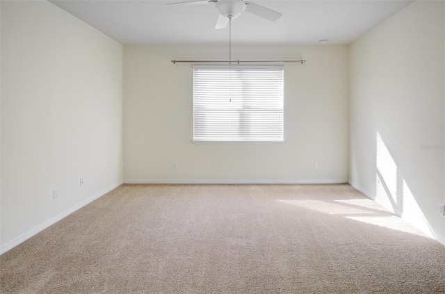 carpeted spare room with baseboards and a ceiling fan