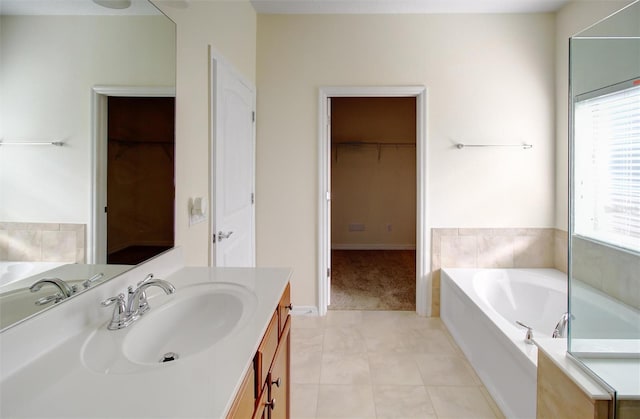 bathroom featuring vanity, a walk in closet, a bath, and tile patterned floors