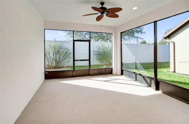 unfurnished sunroom featuring a ceiling fan and a wealth of natural light