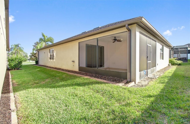 back of house featuring a yard, ceiling fan, and stucco siding