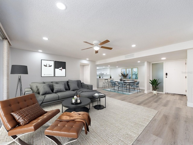 living area featuring visible vents, a textured ceiling, recessed lighting, light wood finished floors, and ceiling fan