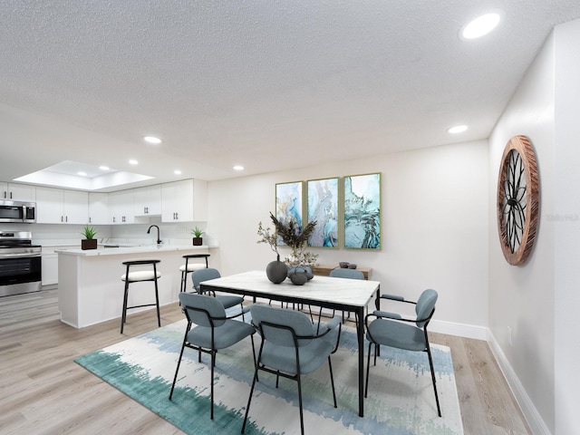 dining room with recessed lighting, light wood-type flooring, baseboards, and a textured ceiling