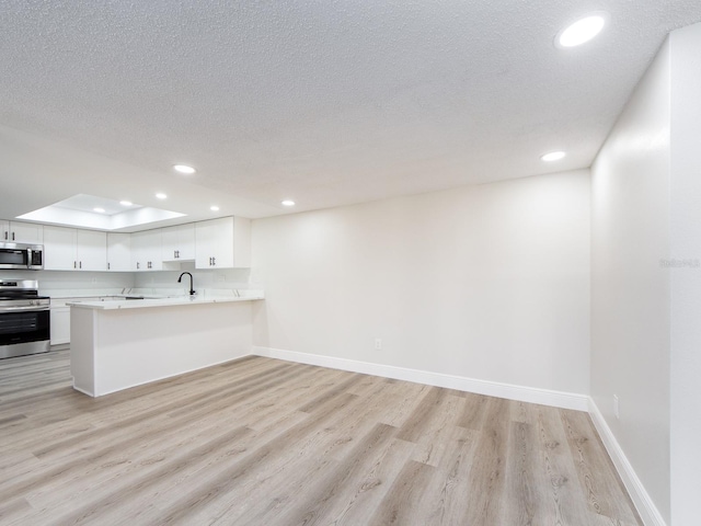 kitchen featuring light wood finished floors, baseboards, light countertops, recessed lighting, and stainless steel appliances