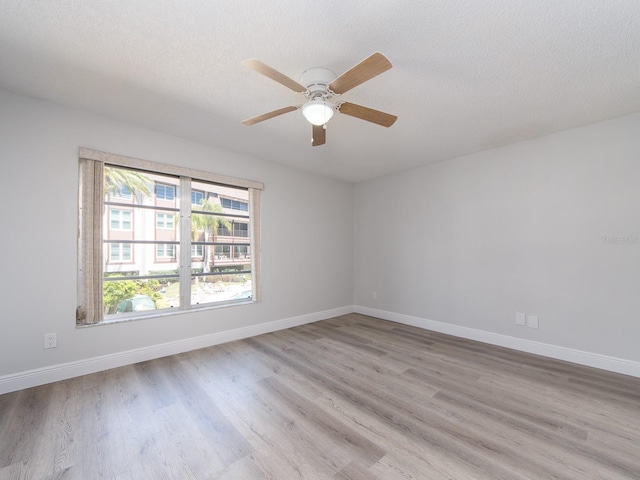 empty room with ceiling fan, baseboards, a textured ceiling, and wood finished floors