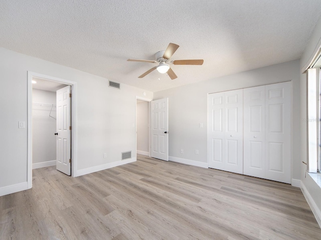 unfurnished bedroom with light wood-style flooring, baseboards, visible vents, and a closet