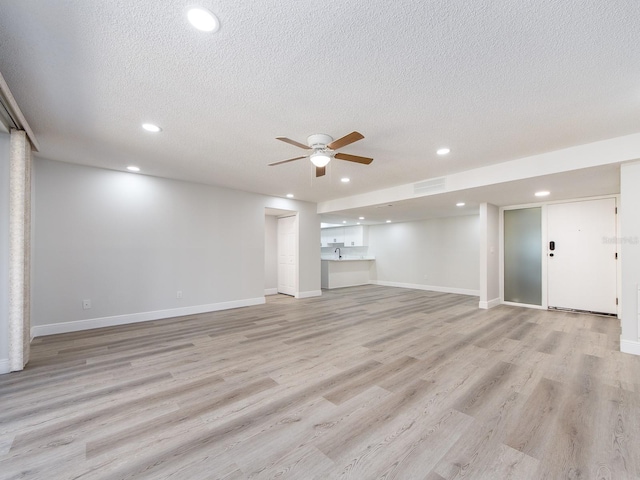 basement featuring visible vents, light wood-style flooring, a textured ceiling, recessed lighting, and ceiling fan